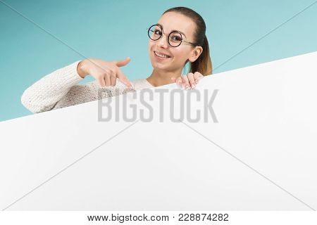 Portrait Of Attractive Happy Woman In Sweater And Round Glasses Isolated On Blue Background Holding 