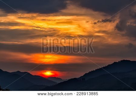 Beautiful Landscape Of A Big Setting Sun Over The Silhouette Of The Mountains, Salciua, Romania