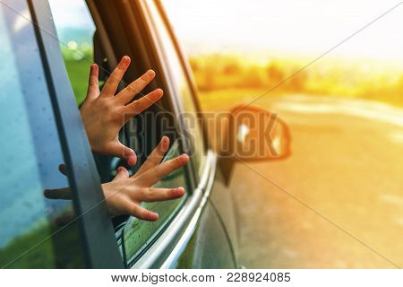 Child Hands In A Car Window During Travel To Vacation. Soft Light Effect.