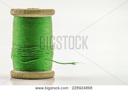 Reel Or Spool Of Green Sewing Thread Isolated On White. Shallow Depth Of Field. Close-up Macro Shot.