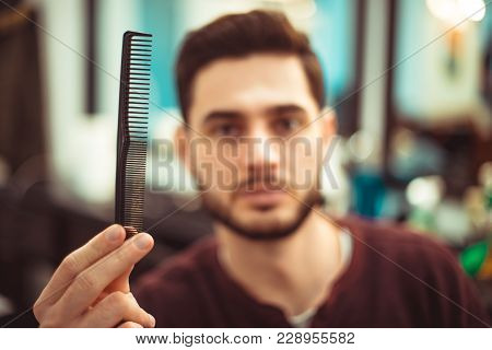 The Concept Of Beauty. A Man Holding A Comb In His Outstretched Hand. Soft Focus.