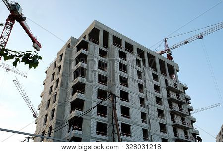 Urban Construction. Jib Cranes Around Modern City Building In Construction Process