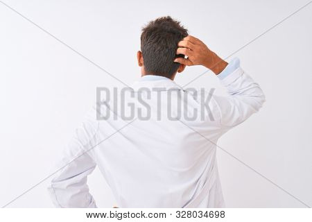 Young handsome sciencist man wearing glasses and coat over isolated white background Backwards thinking about doubt with hand on head