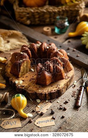 Tasty Homemade Baked Pumpkin Bundt Cake With Chocolate On Top Stands On Wooden Board On Rustic Table