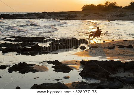 A Man Sitting In An Armchair And Admiring The Sunset. The Concept Of Happiness, Relaxation, Vacation