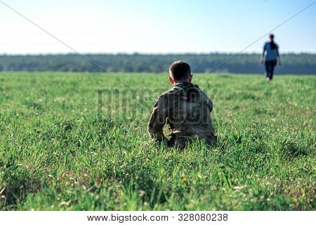 A Green Field On A Summer Day Sits A Man From Whom A Woman Leaves In The Distance. Divorce Couple In