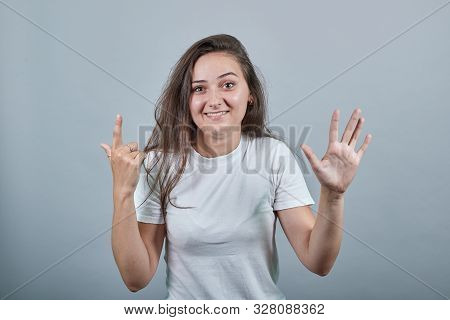 Woman With Long Hair Over Colorful Wall Counting Seven With Fingers. Person Shows Two Hands With Cur