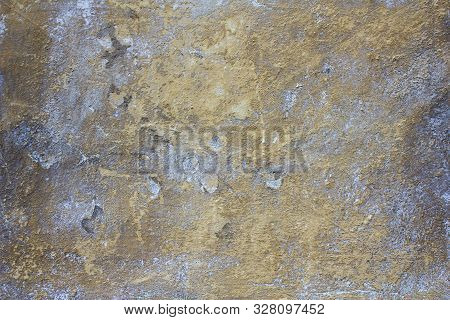 Old Concrete Yellow Ragged Wall With Blue Spots Of Paint, Damage And Scratches. Rough Surface Textur