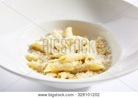 Delicious penne four cheeses close up. Traditional italian cuisine restaurant menu item. Tasty pasta isolated on white background. Macaroni dish with formaggi, mozzarella, gorgonzola and fontina