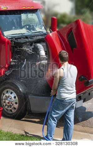 Young Man Washing A Semi-truck While It Is Parked On The Street In Front Of His Home.