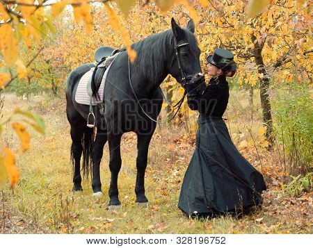 Horsewoman Girl In A Black Dress Leads A Black Horse