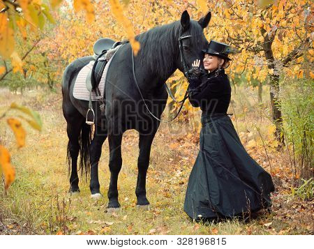 Horsewoman Girl In A Black Dress Leads A Black Horse