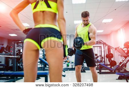 Gorgeous Woman Posing Near Sports Equipment At A Gym Looking Straifht In Front Of Her. View From The