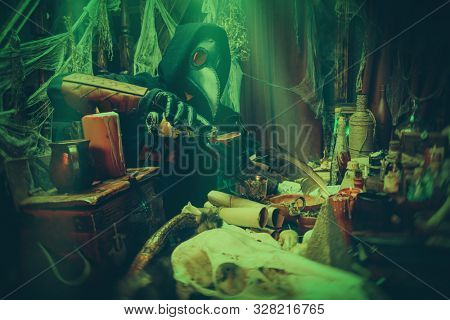 The plague doctor is working at his desk, inventing a cure for bubonic plague. The atmosphere of mysticism. Historical reenactment. Halloween. 