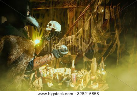The plague doctor is working at his desk, inventing a cure for bubonic plague. The atmosphere of mysticism. Historical reenactment. Halloween. 