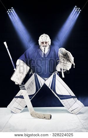 Hockey Goalie Stands In The Spotlight Ready To Catch The Puck.hockey Goalie In Complete Hockey Gear 