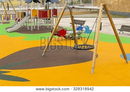 Empty Playground With Swings And Safe Rides With Anti-traumatic Bright Rubber Crumb Coating. Games F