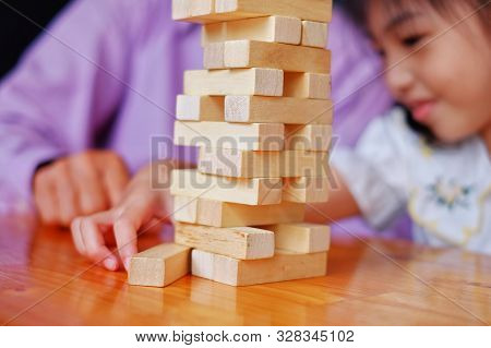 An Grandfather Is Teaching His Granddaughter To Play A Block Wood Tower Game.