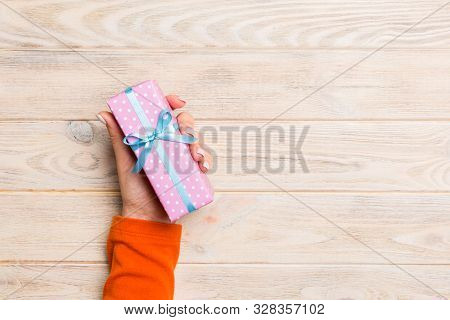 Top View Woman Hands Holding Present Box With Colored Bow On Yellow Rustic Wooden Background With Co