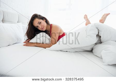 Young Attractive Woman In Red Underwear Lying In Bed In Bright Bedroom Looking Sexy