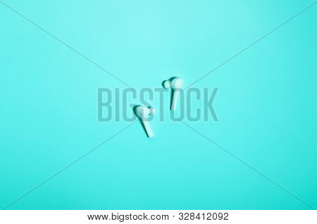 Wireless In Ear Headphones On Blue Background Close Up. Minimal Music Concept. White Earphones Flat 