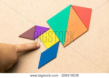 Color Tangram In Rocket Shape With Hand At The Base On Wood Background (concept For Startup, New Exp