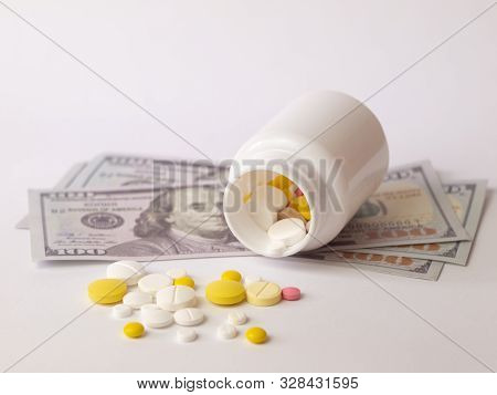 Healthcare Savings And Expencive Medicine Concept. Pills Scattered Over Dollar Banknotes. Bottle Of 