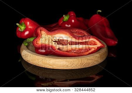 Group Of Three Whole One Half Of Sweet Red Bell Pepper On Bamboo Plate Isolated On Black Glass
