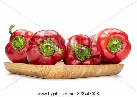 Group Of Four Whole Sweet Red Bell Pepper On Wooden Square Plate Isolated On White Background