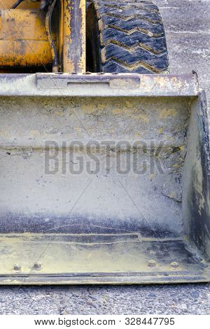 Construction Tractor. The Bucket Lies On The Pavement, The Old Wheels Are Scratched. Working Old Tec