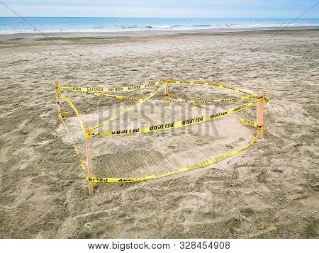 Protected Sea Turtle Nest. Barricaded Sea Turtle Nest With Yellow Tape And Ground Meshing On The Bea