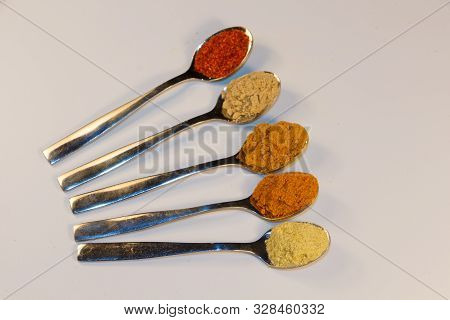 Different Spices In Powder In Metal Teaspoons