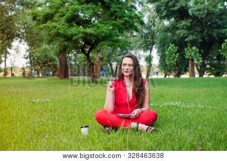 Portrait Of Young Smiling Business Woman In Red Suit In Earphones, Doing Online Learning Cources And