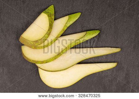 Group Of Five Slices Of Fresh Green Pear Flatlay On Grey Stone