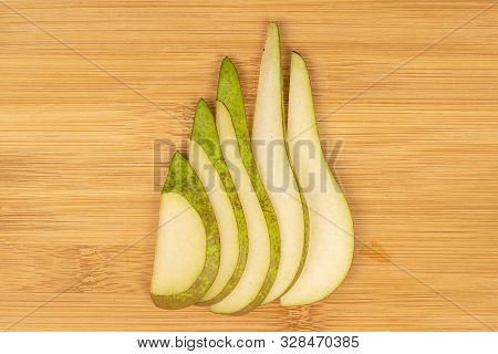 Group Of Five Slices Of Fresh Green Pear Flatlay On Light Wood