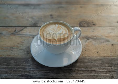 Cup Of Coffee With Latter Art Sitting On A Wooden Table