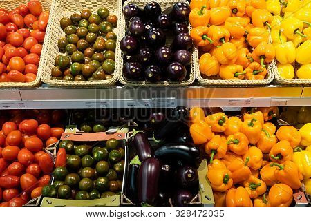 Supermarket Counter With Wicker Baskets And Lug Boxes With Fresh Red And Green Variety Of Tomatoes, 