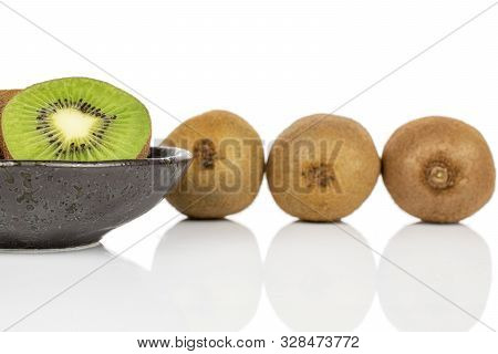 Group Of Three Whole One Half Of Exotic Brown Kiwi On Glazed Bowl Isolated On White Background