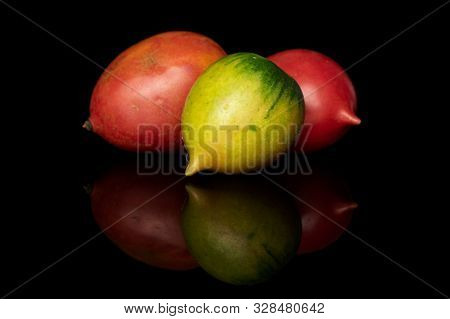 Group Of Three Whole Fresh Tomato De Barao Isolated On Black Glass