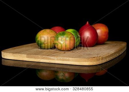 Group Of Six Whole Fresh Tomato De Barao On Bamboo Cutting Board Isolated On Black Glass