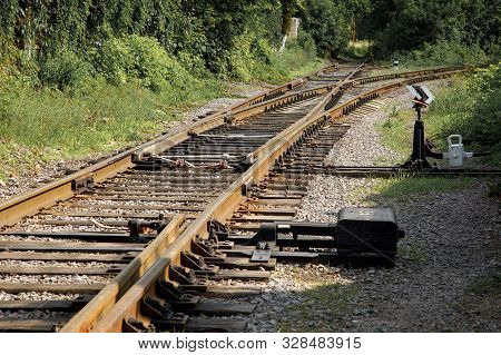 Railway Junction Among Green Plants On A Sunny Day. The Honor Of The Rails Ends, One Of The Branches