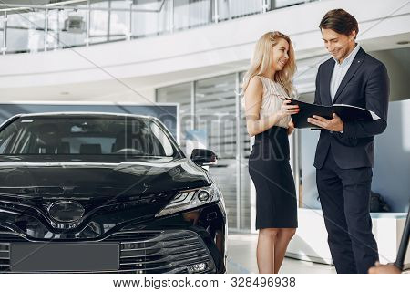 Stylish And Elegant Couple In A Car Salon