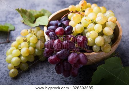 Healthy Fruits Red And White Wine Grapes On Stone Backgrounds. Grapes In Wooden Bowl