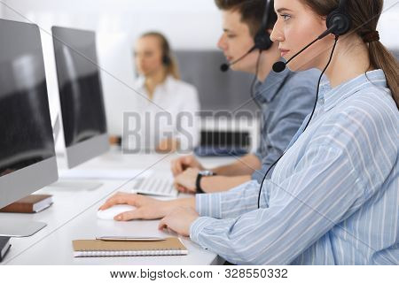 Call Center. Group Of Casual Dressed Operators At Work. Focus On Business Woman In Headset At Custom