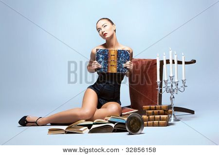 Sesión de moda de mujer sexy joven leyendo libros en ropa interior agradable