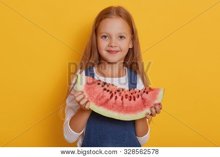 Indoor Shot Of Little Charming Girl With Portion Of Sweet Watermelon In Her Hands, Charming Blonde M