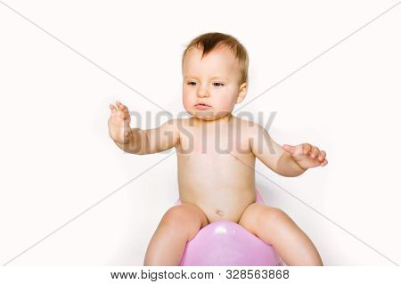 Baby Girl Sits On A Childrens Pot, Toilet On A White Background