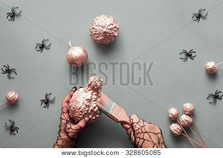 Creative Halloween Flat Lay On Grey Paper Background With Pumpkins And Spiders, Copy-space. Hands In