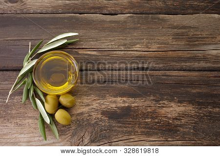 Olive Oil And Olive Branch Backlit On Old Wooden Background