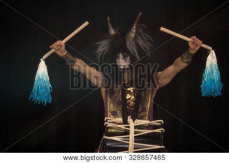 Demon From Japanese Mythology. Portrait Of An Artist Drummer Taiko In A Wig With Horns And Demonic M